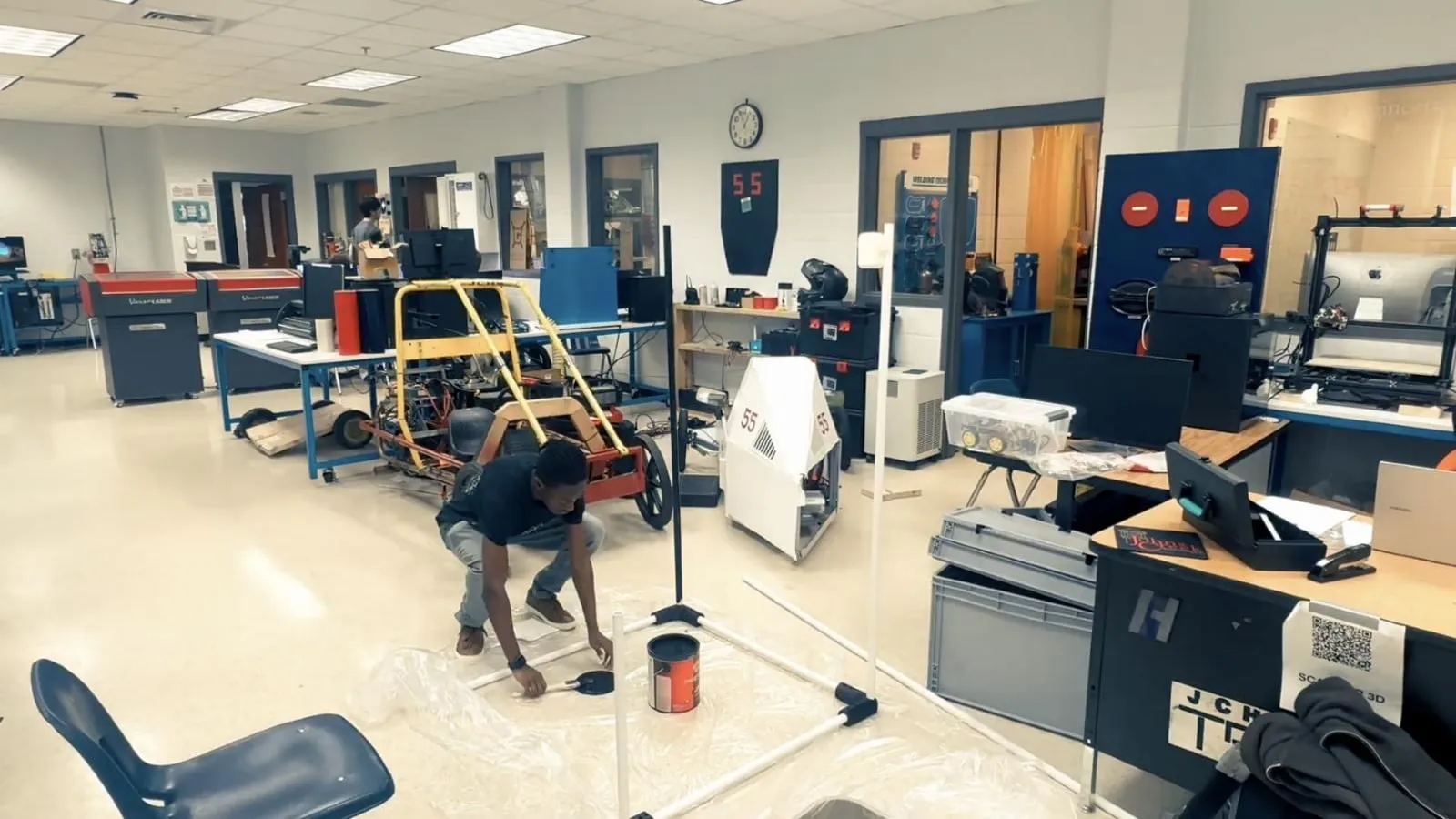 A student assembling a PVC frame on the floor of a school engineering lab